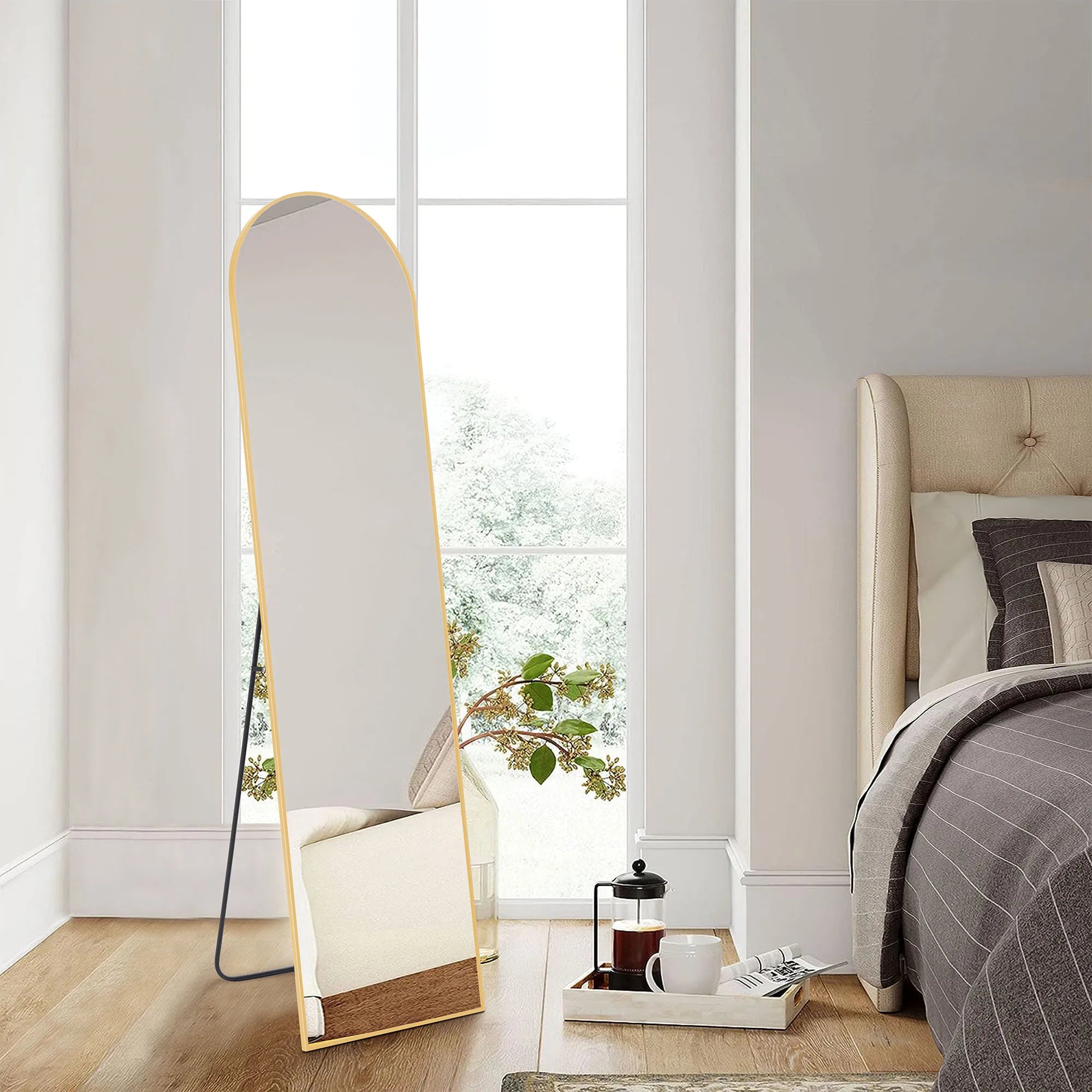 TerraFlow round top gold floor mirror in a minimalist bedroom.